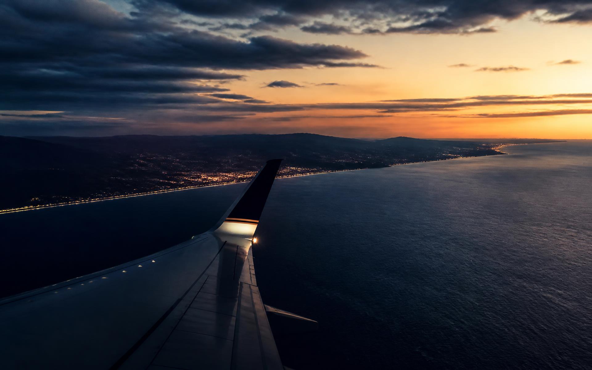 Vista da asa de um avião sobre o litoral ao anoitecer